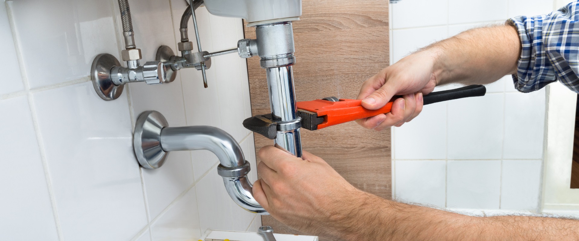 Male Plumber Fixing Sink In Bathroom